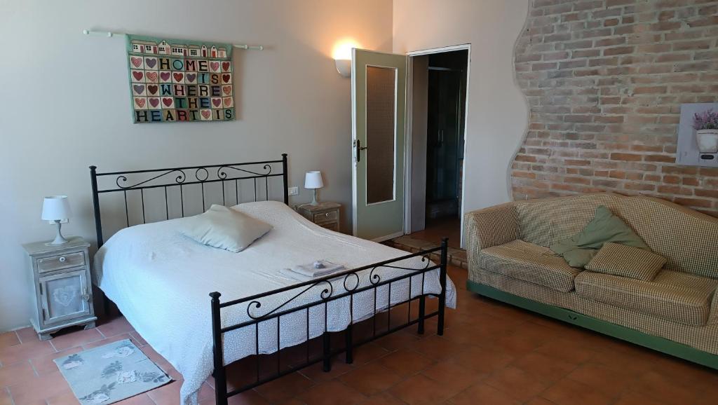 La Locanda Del Molino في Fortunago: غرفة نوم بسرير وكرسي وجدار من الطوب