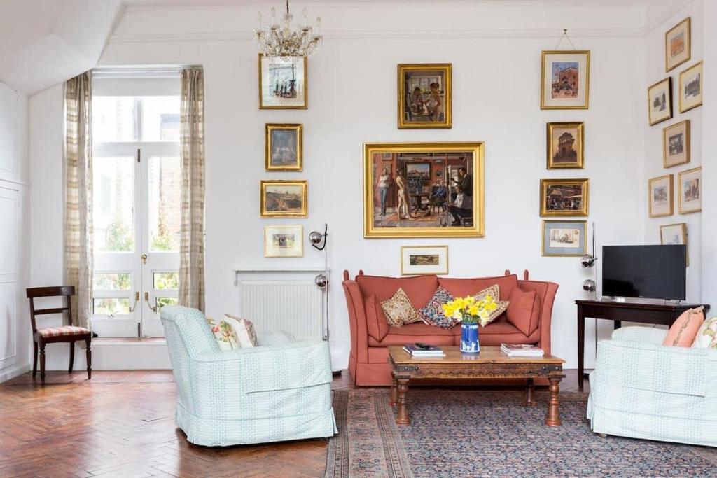 sala de estar con sofá rojo y 2 sillas en Artistic 1bed flat with patio in South Kensington, en Londres