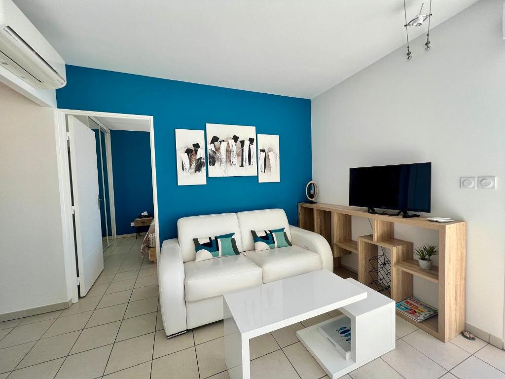 un salon avec un canapé blanc et une télévision dans l'établissement Calypso, appartement Vue mer, à La Ciotat