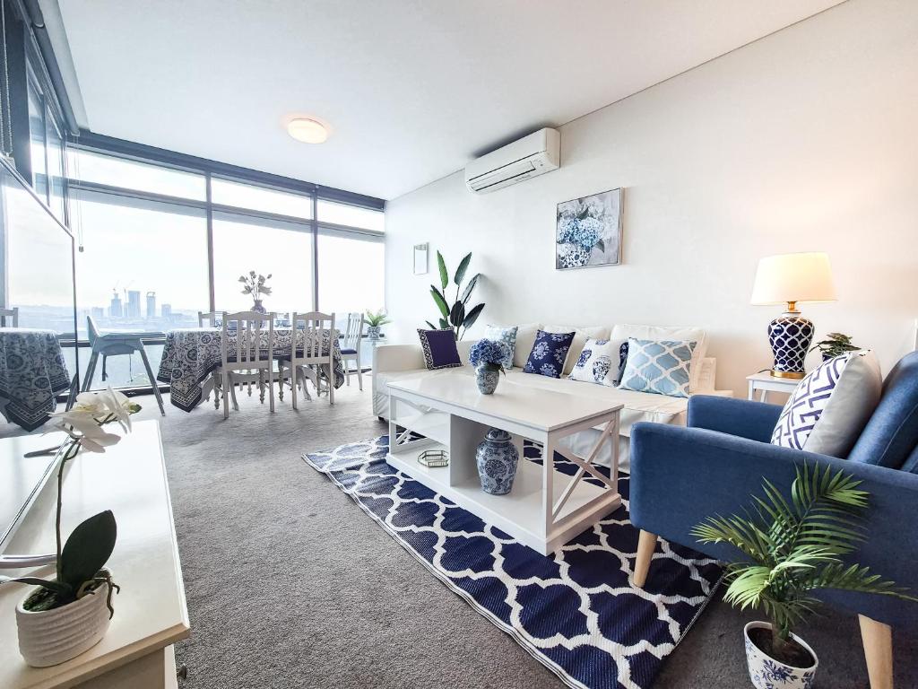 ein Wohnzimmer mit einem Sofa und einem Tisch in der Unterkunft Hamptons Style 2BR & kid room w view in Olympic Park in Sydney