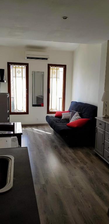 - un salon avec un canapé noir et 2 fenêtres dans l'établissement JOLI STUDIO CLIMATISE PROXIMITE PORTS ET PLAGES, à La Ciotat