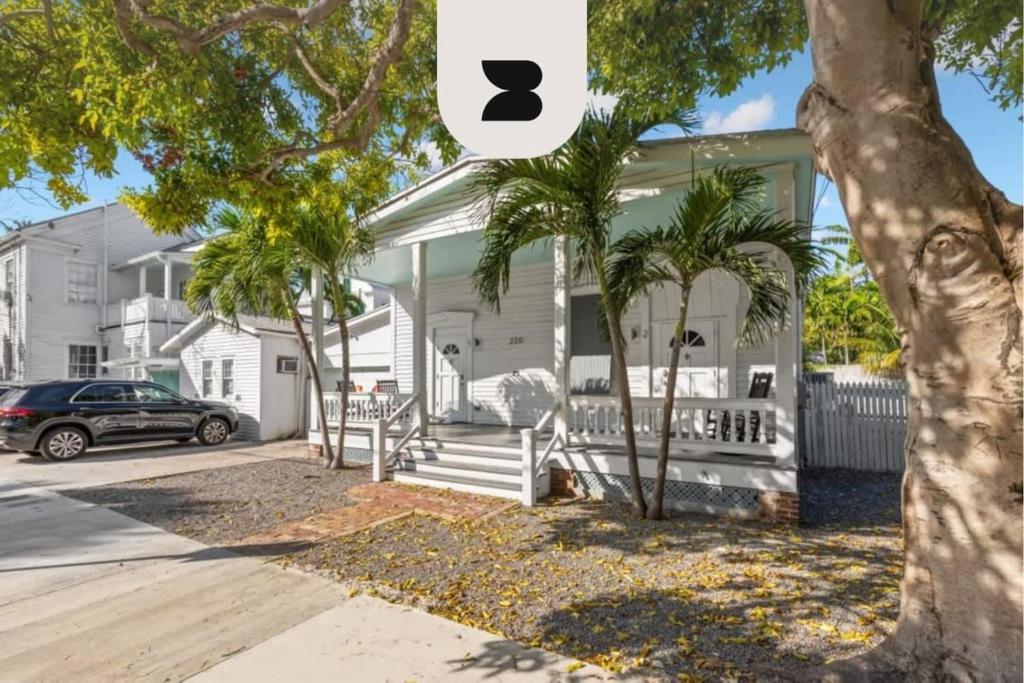 une maison avec des palmiers devant elle dans l'établissement Mesa House, Dos by Brightwild-Unreal Location, à Key West