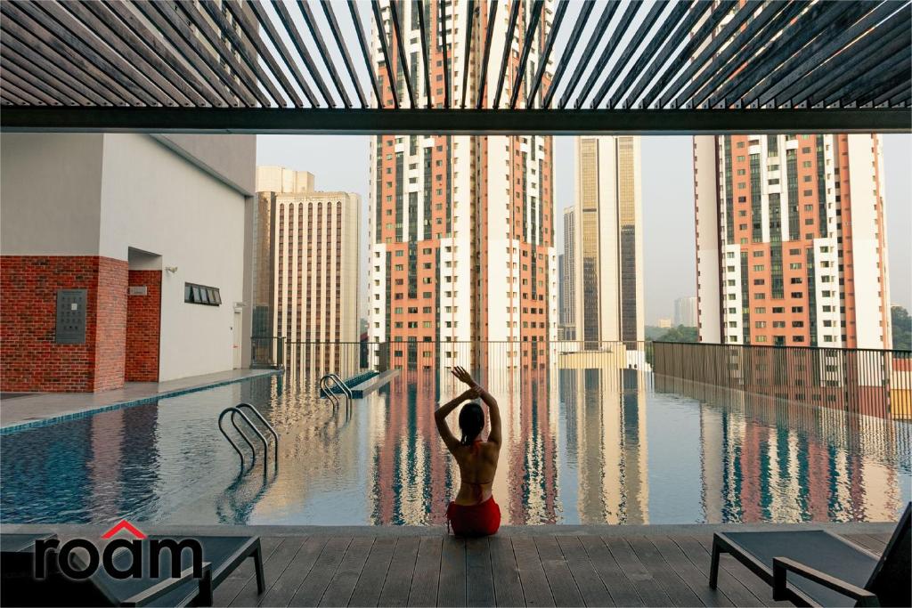 una mujer está parada frente a una piscina en Chambers Residence Kuala Lumpur by Roam, en Kuala Lumpur