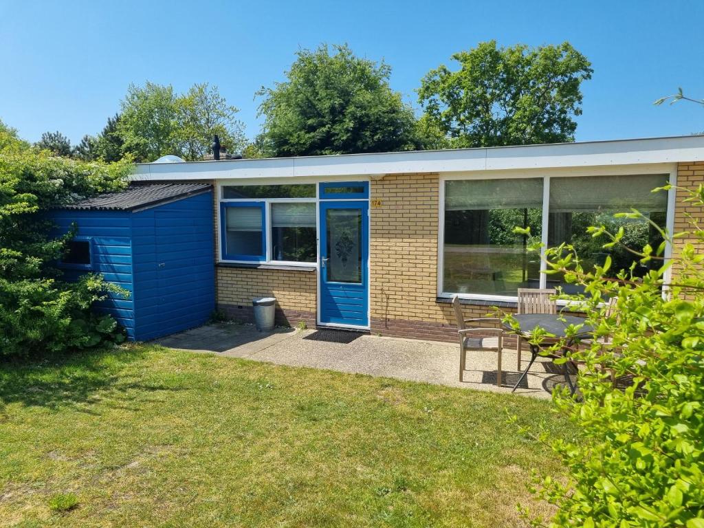 una casa con una puerta azul en un patio en Zilt Zand, en De Koog