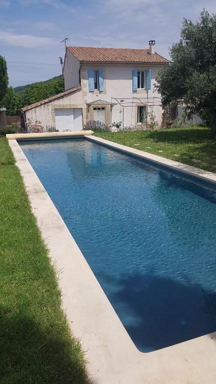 una gran piscina azul frente a una casa en Maison de charme avec bassin de nage 