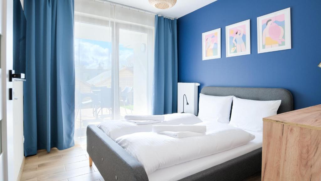 een slaapkamer met een bed met een blauwe muur bij Apartamenty Sun & Snow Villa Verona in Mielno