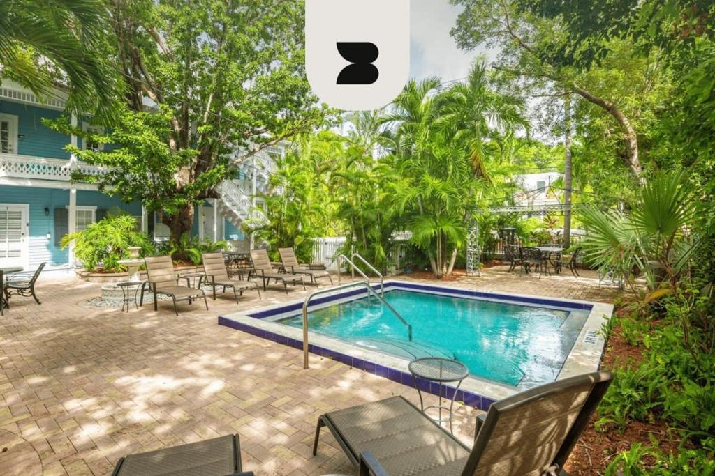 uma piscina num quintal com cadeiras e mesas em Sky Loft in Key West by Brightwild em Key West