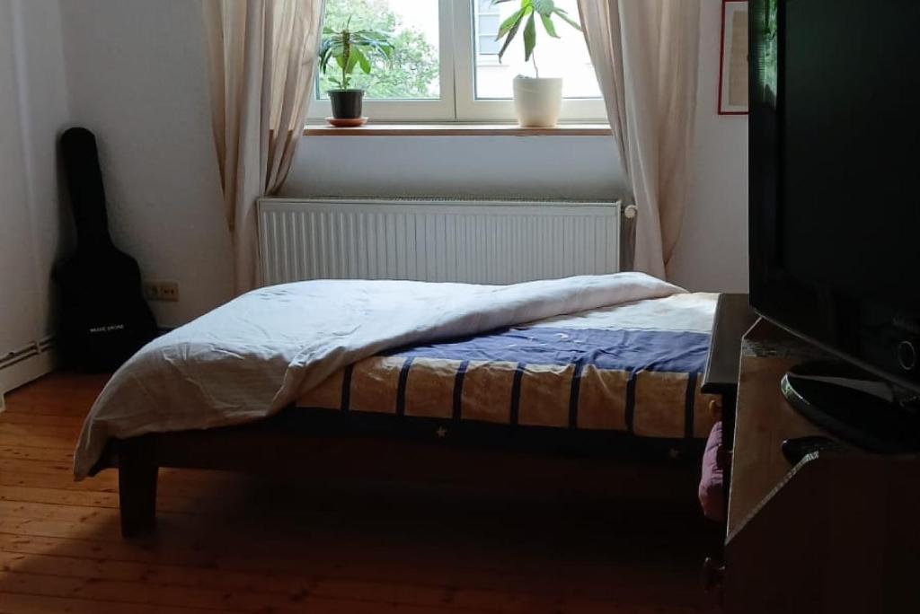 a bed in a room with a window and a television at Private Rooms in Hannover