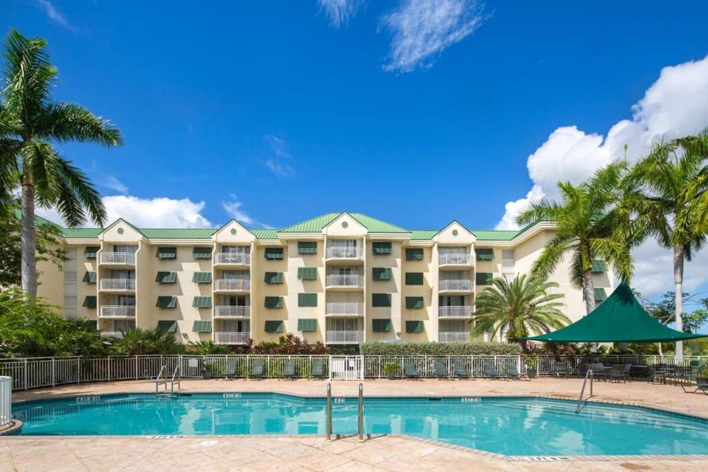 a large hotel with a swimming pool and palm trees at The Tortuga by Brightwild-Pool, Parking & Pets! in Key West