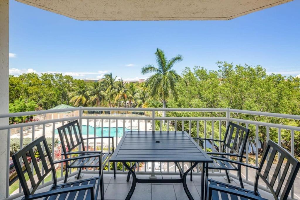 基韋斯特的住宿－The Barbados by Brightwild-Bright Condo w Pool，一个带桌椅的阳台和一个游泳池
