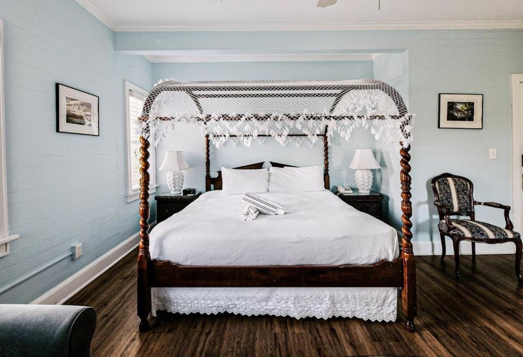 a bedroom with a canopy bed and two chairs at Deluxe King with Balcony by Brightwild- at James House with Parking! in Key West