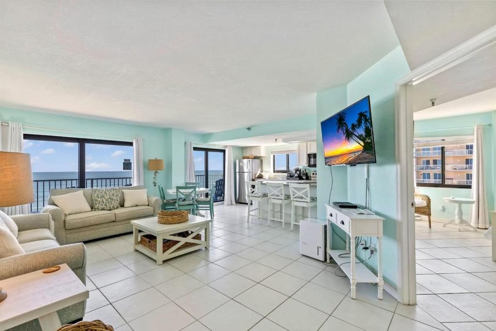 a living room with a couch and a tv at Ocean Front Penthouse with Incredible Views! Sunglow Resort 1003 by Brightwild in Daytona Beach Shores