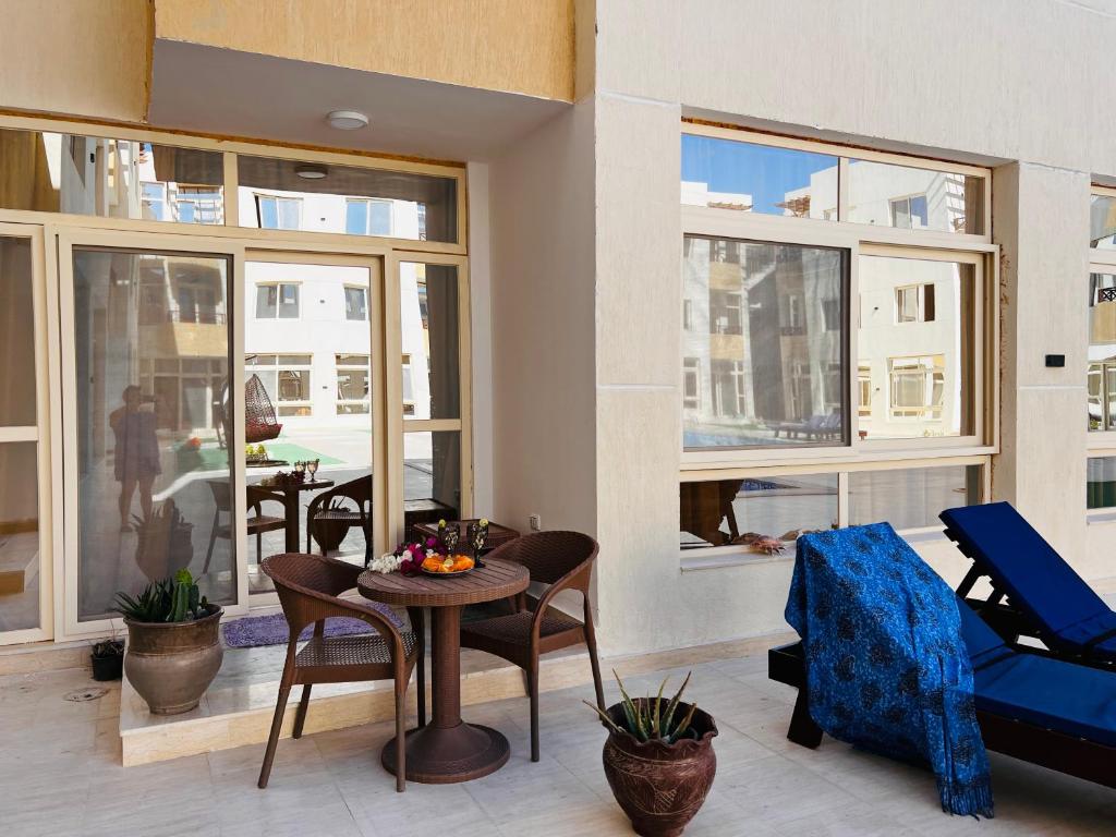 Port Ghalib Apartments في بورت غالب: غرفة معيشة مع طاولة وكراسي ونوافذ