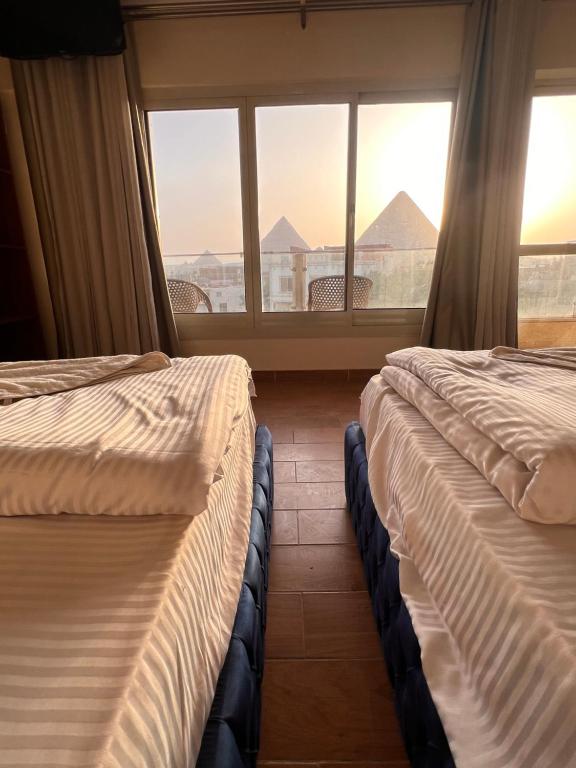 twee bedden in een kamer met een raam bij Sphinx and Pyramids INN in Caïro