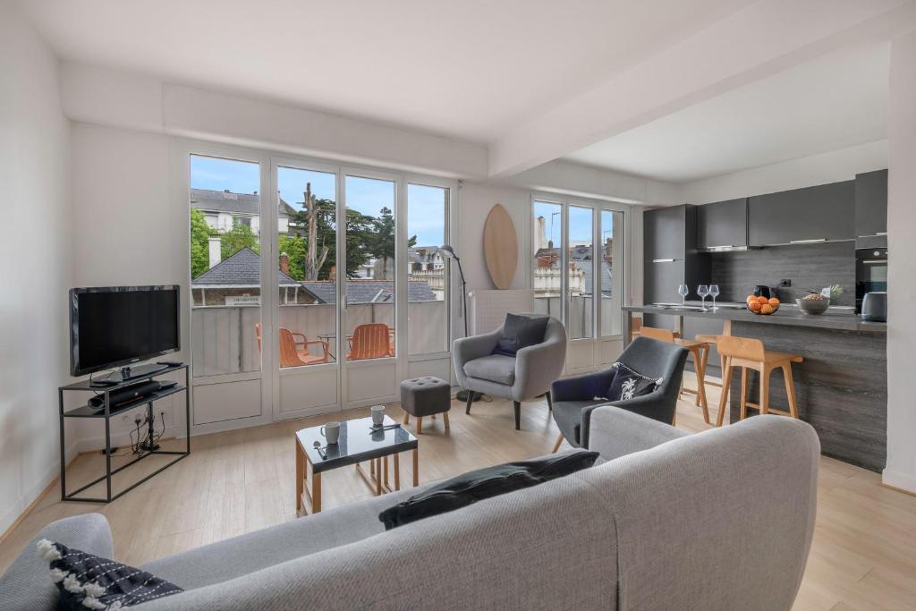 Il comprend un salon avec un canapé gris et une cuisine. dans l'établissement Découverte en duo en plein centre de la Baule, à La Baule