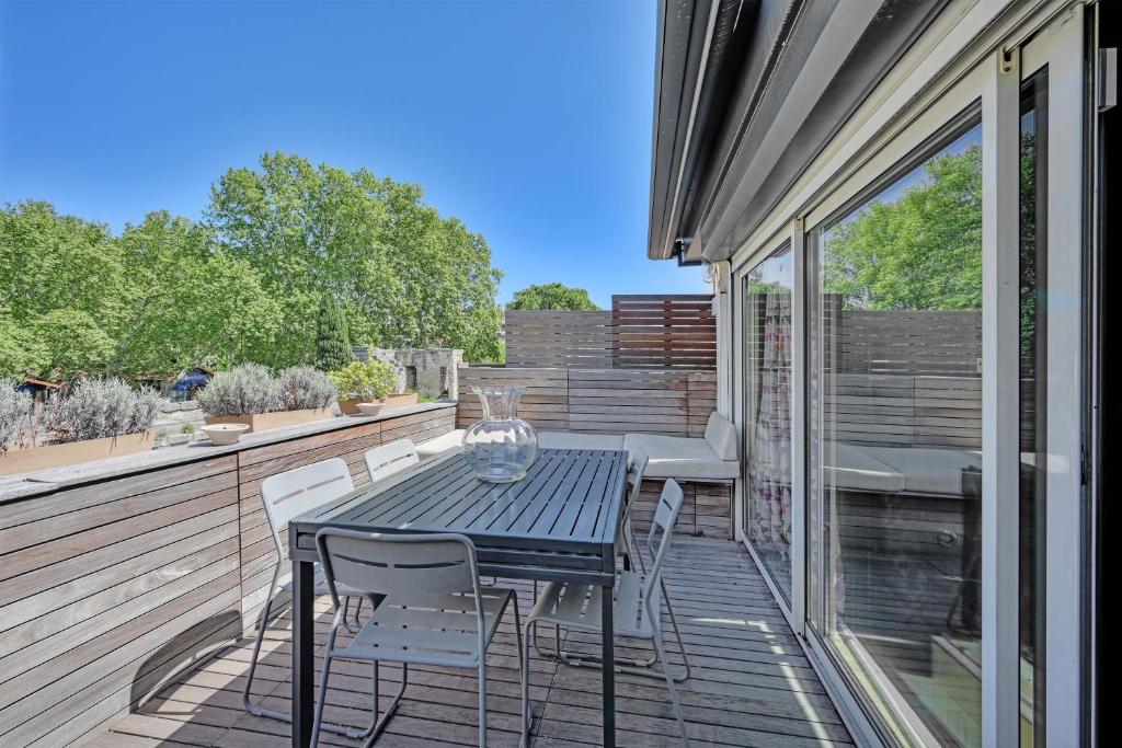 un patio avec une table et des chaises sur une terrasse dans l'établissement Maison Arti - Parking - Vue Palais des Papes - Rooftop, à Avignon