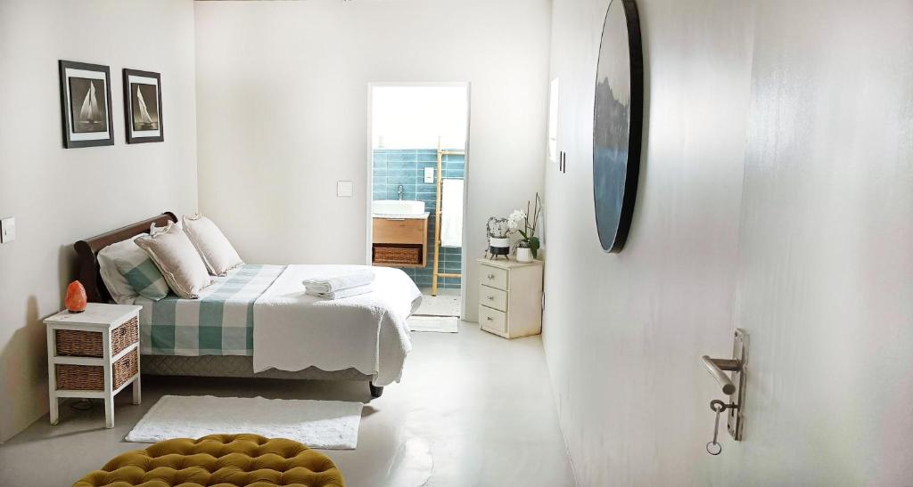 een witte slaapkamer met een bed en een spiegel bij Sea Breeze Cottage in Kaapstad