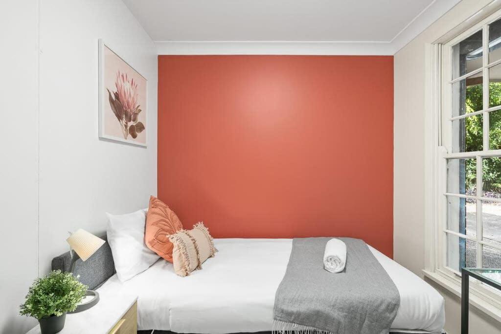 1 dormitorio con 1 cama con pared de color naranja en Single Room in Pymble Sleeps 1, en Pymble