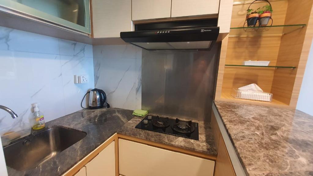 a small kitchen with a stove and a sink at Vanilla One Residence Apartment Batam in Batam Center