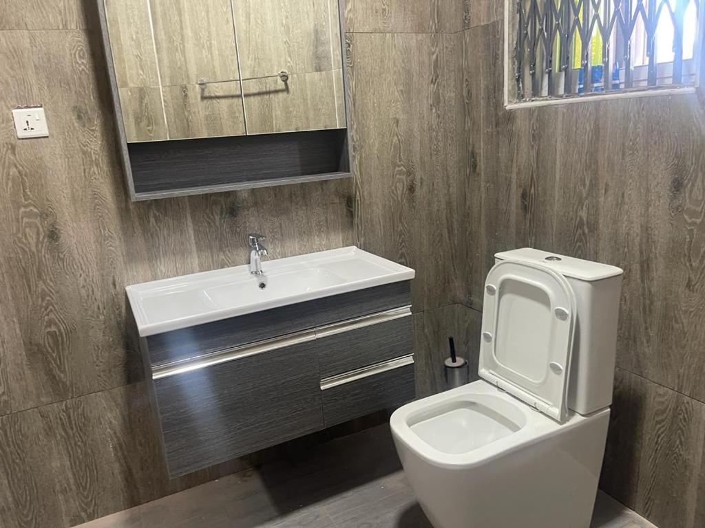 a bathroom with a white toilet and a sink at THE GREEN CONDO in Elmina