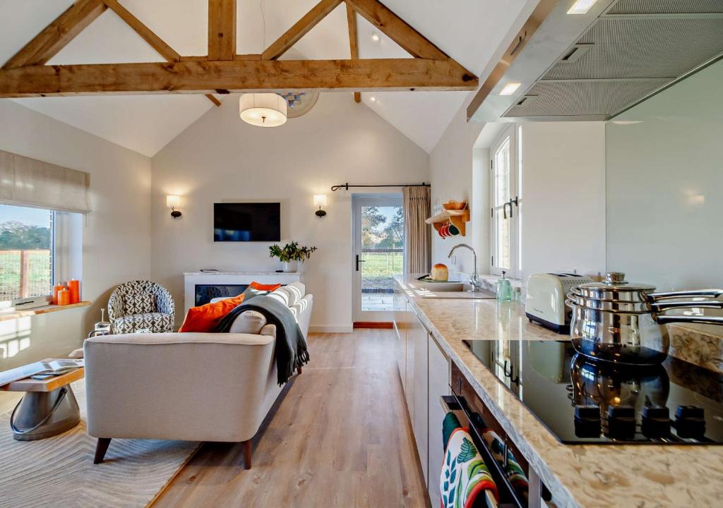 a kitchen and living room with a couch and a table at The Domini Cowshed at Village Farm in Market Weston