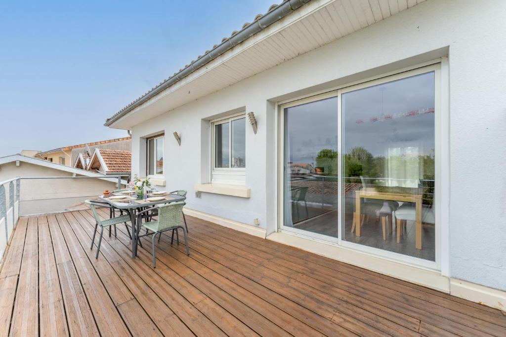 eine Holzterrasse mit einem Tisch und Stühlen darauf in der Unterkunft Nice apartment with terrace in Le Bouscat - Welkeys in Le Bouscat