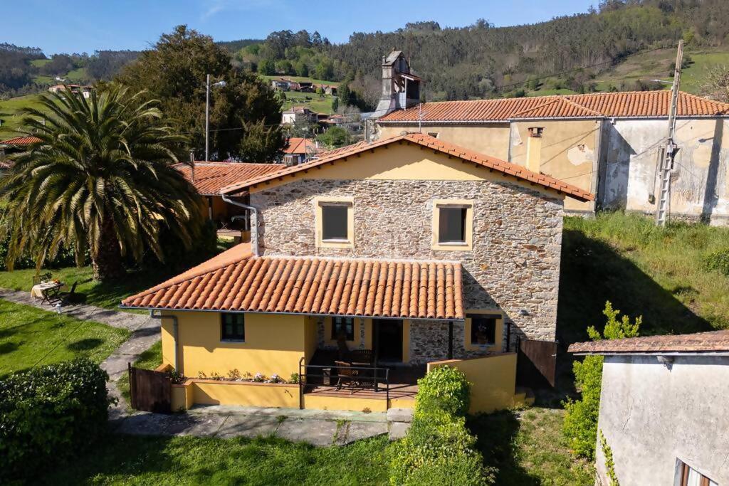 una pequeña casa de piedra con techo rojo en La Casona Del Cura III, en Pravia