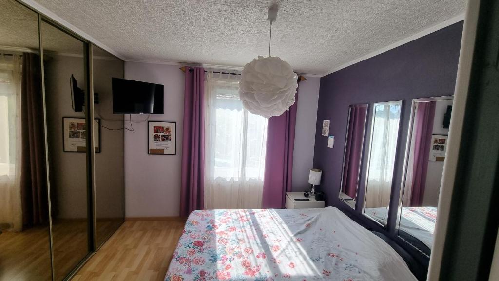 a bedroom with purple walls and a bed and a mirror at Agréable maison au calme in Wittenheim