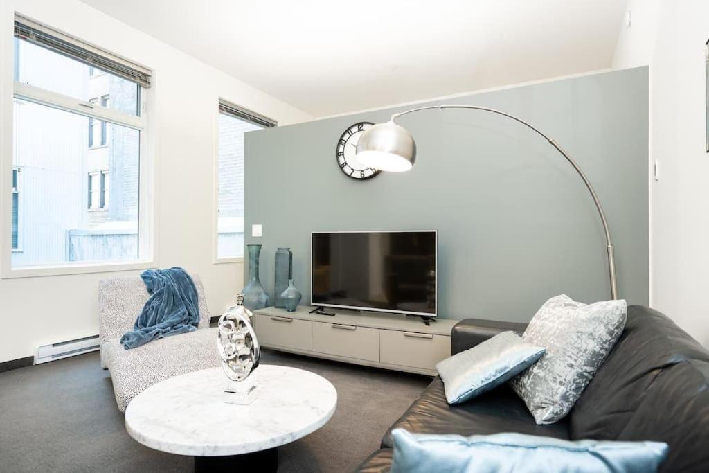 sala de estar con sofá y TV en Premium 2BD Loft DT Heated Parking Rooftop Patio BBQ Gym Coffee en Winnipeg