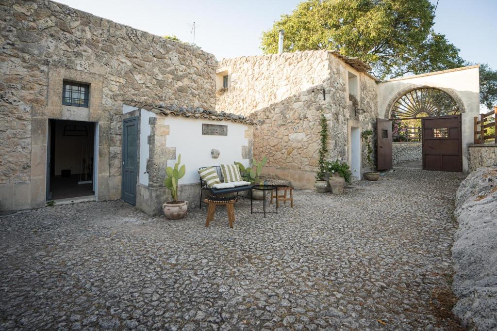un patio de un edificio de piedra con mesa y sillas en Natura Escape in Val di Noto, en Noto