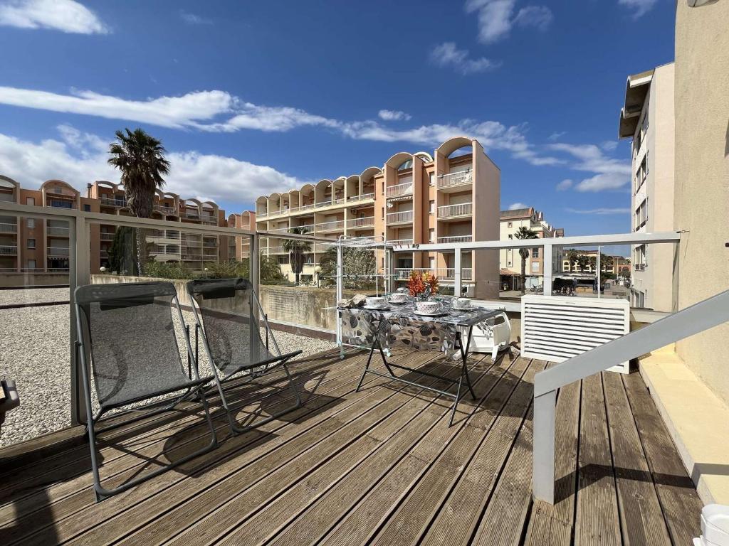 - un balcon avec une table au-dessus d'un bâtiment dans l'établissement Appartement rénové avec 2 pièces et parking privé à Gruissan, proche plage du Grazel - FR-1-229-883, à Gruissan