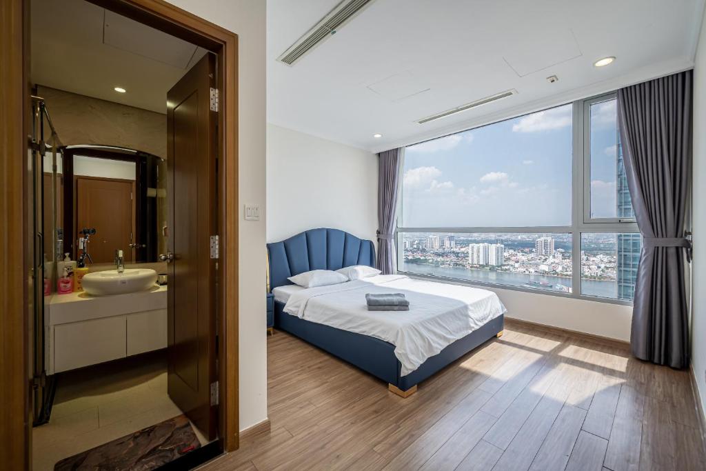 a bedroom with a bed and a bathroom with a window at VINHOMES LANDMARK CONDOTEL SUITE in Ho Chi Minh City