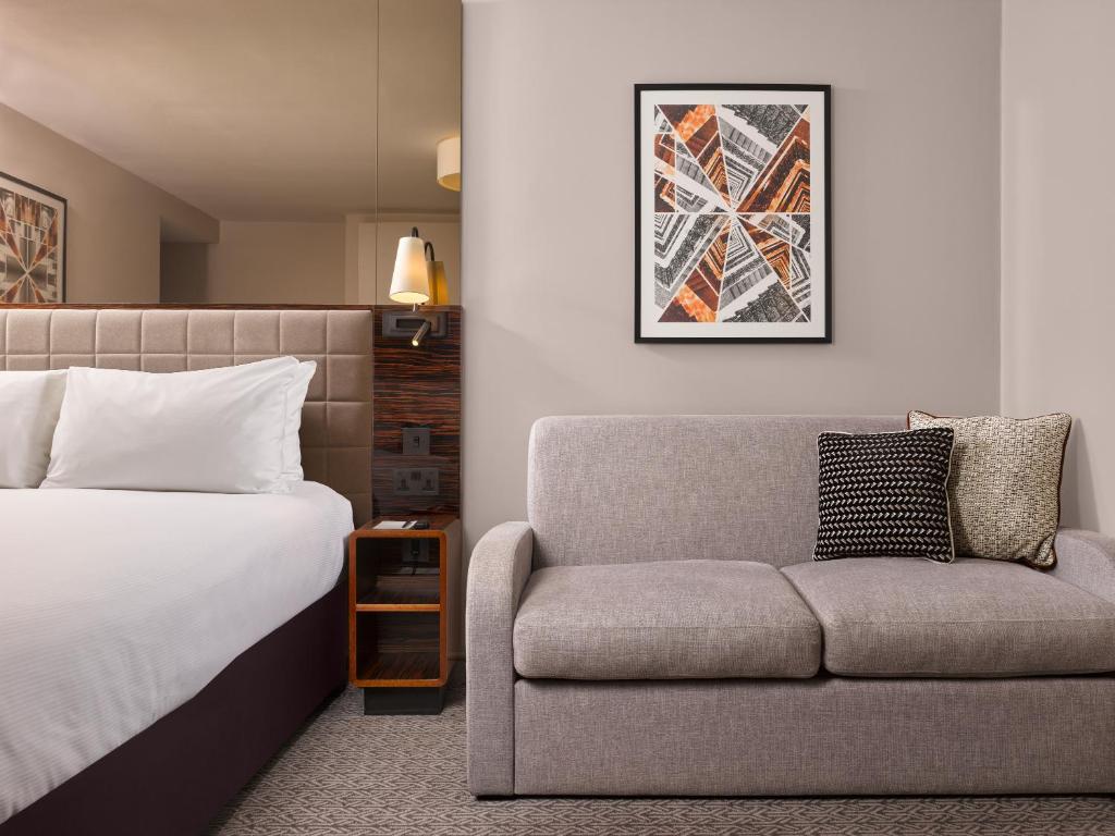 a hotel room with a bed and a couch at Strand Palace in London
