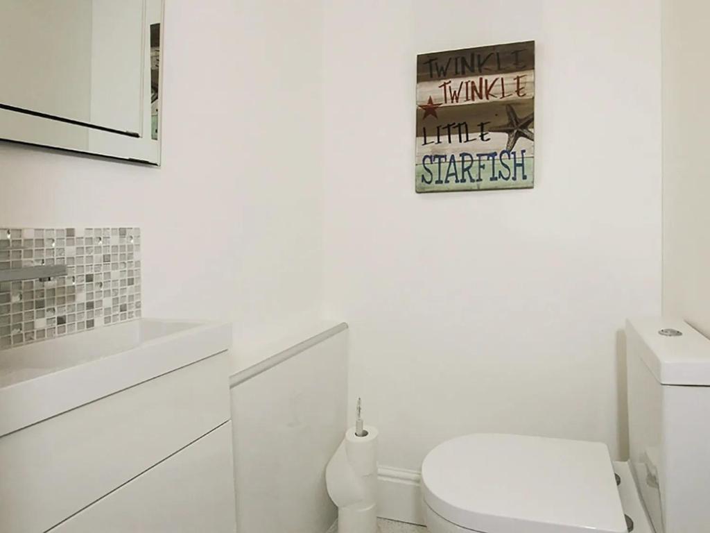 a white bathroom with a toilet and a picture on the wall at Waterside - Luxury Menai Bridge Holiday Home - 4 Bed 4 Bath in Menai Bridge