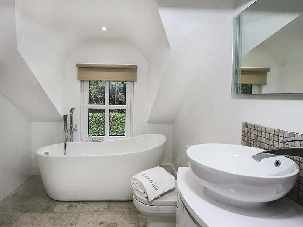 a white bathroom with a tub and a sink at Waterside - Luxury Menai Bridge Holiday Home - 4 Bed 4 Bath in Menai Bridge