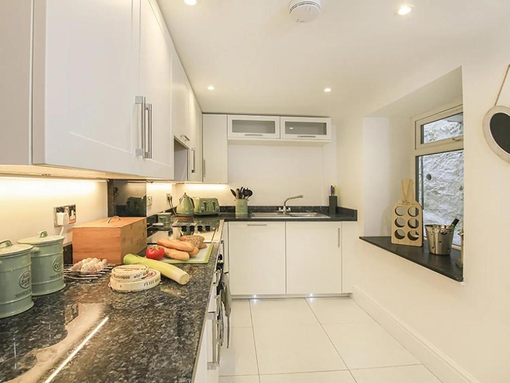 a kitchen with white cabinets and a black counter top at Waterside - Luxury Menai Bridge Holiday Home - 4 Bed 4 Bath in Menai Bridge