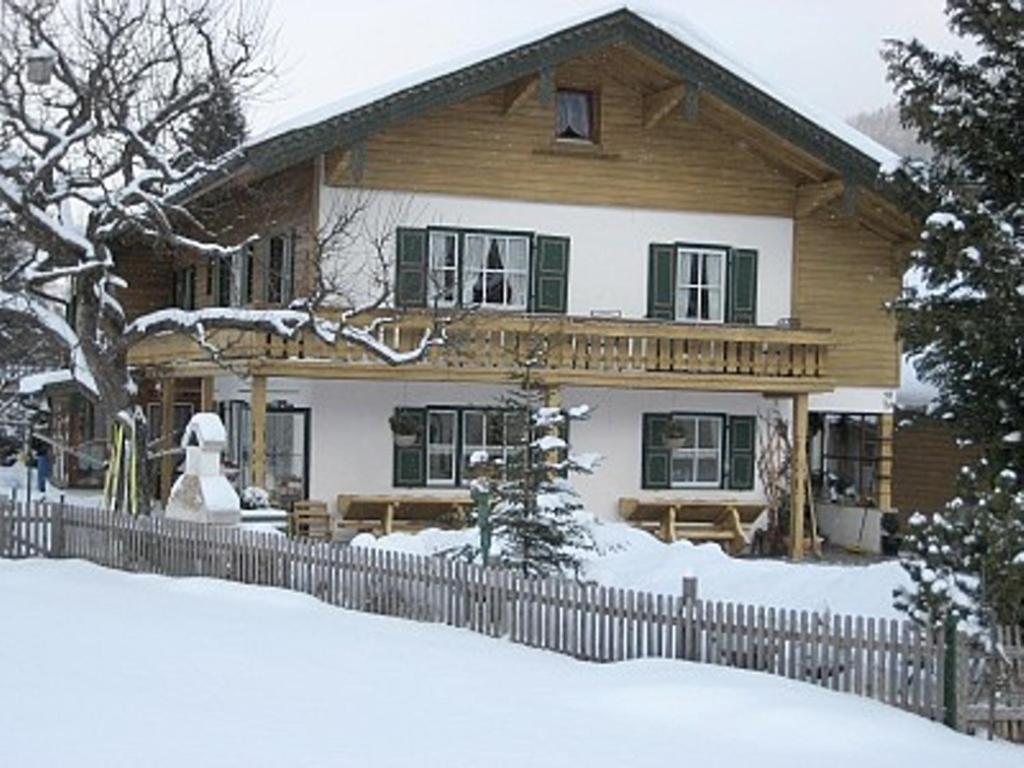 a wooden house with a fence in the snow at Gästehaus Burghartswieser in Bernau am Chiemsee