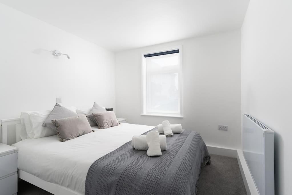 a white bedroom with a large bed with two white towels at Beautiful 1 bedroom ground floor new apartment in old Cornwall in St. Just