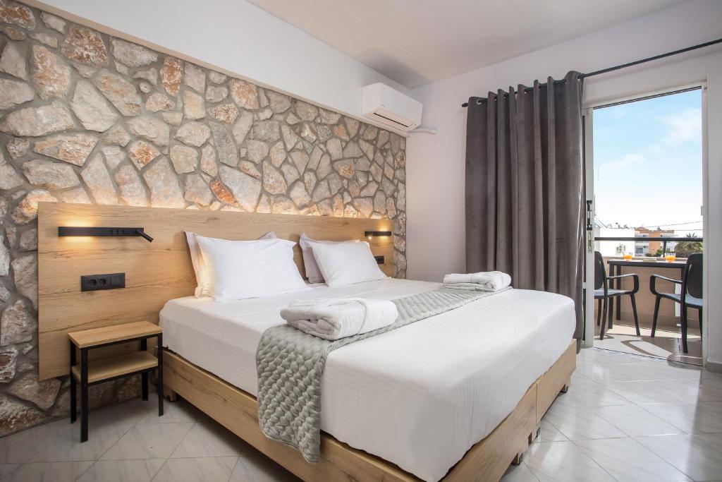 1 dormitorio con 1 cama grande y pared de piedra en Jimmy’s Garden en Faliraki