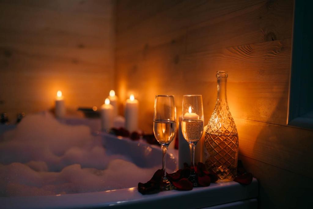 two wine glasses and a bottle on a table with candles at Apartament Plus in Mrągowo