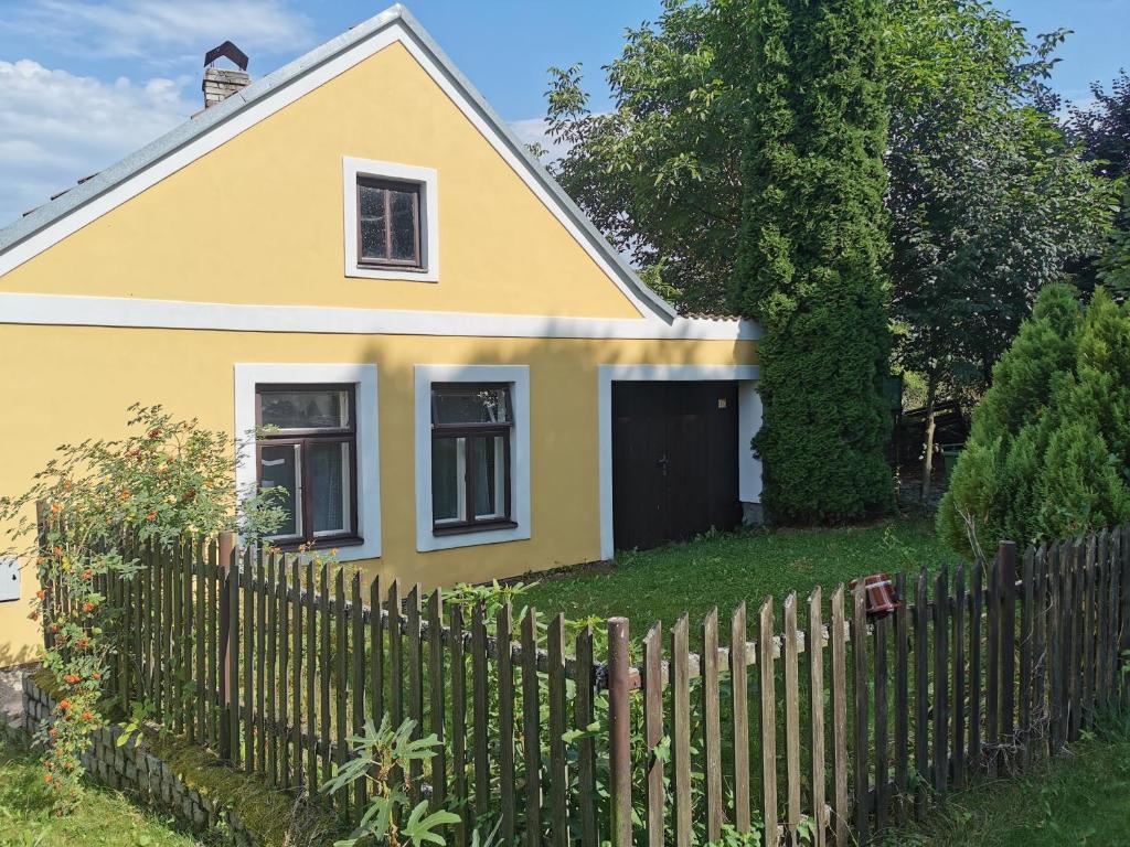 uma casa amarela atrás de uma cerca de madeira em Vejminek Malý Statek 