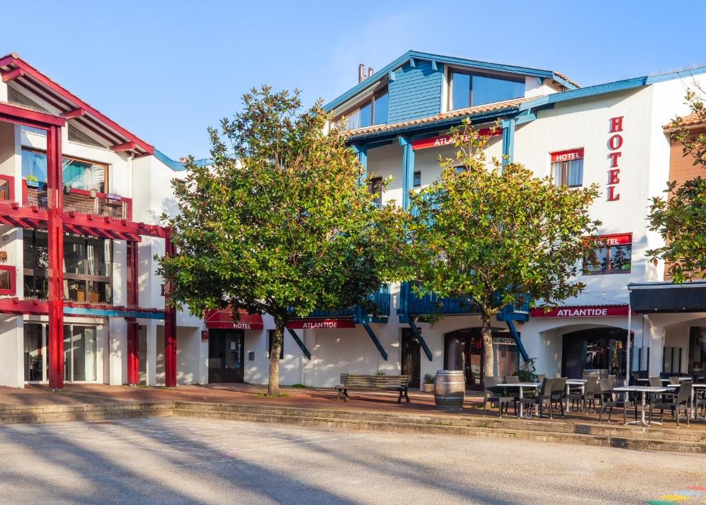 un grupo de edificios en una calle con árboles en Hotel Atlantide, en Biscarrosse