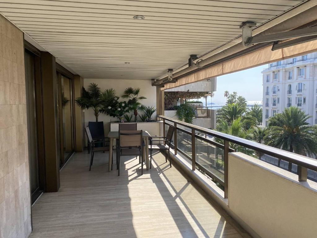 - un balcon d'un immeuble avec une table et des chaises dans l'établissement Cannes Croisette - Appartement 3 Pièces Résidence GRAY D'ALBION, à Cannes