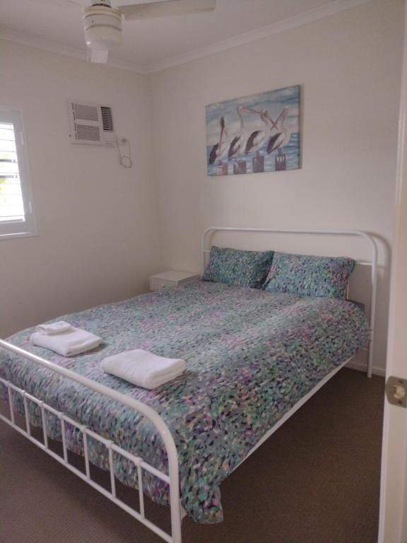 ハービーベイにあるOcean Breeze Apartments Hervey Bayのベッドとタオル2枚のある寝室