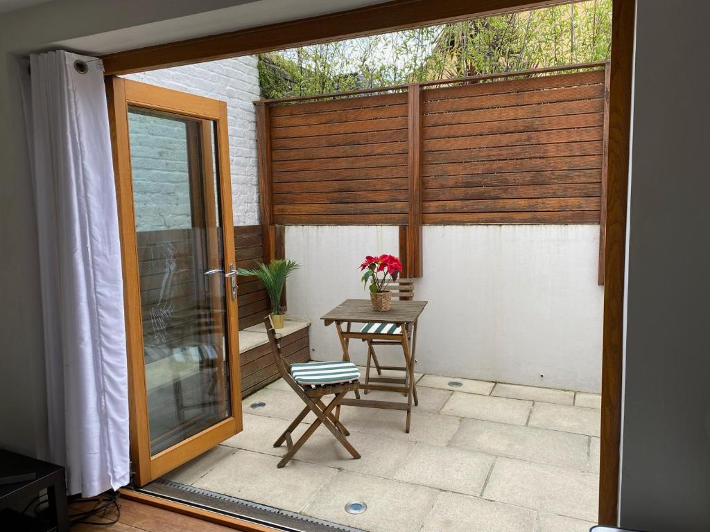un patio con una mesa y una puerta de cristal en Luxury Putney Riverside Apartment, en Londres