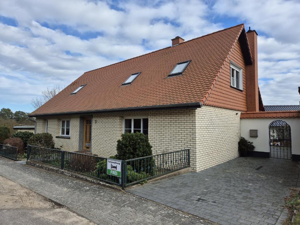 uma casa com um telhado castanho e uma cerca em Ferienwohnung Witt em Neustrelitz