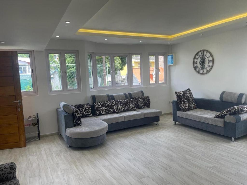 a living room with couches and a clock on the wall at Spacious Flat in Port Louis in Port Louis