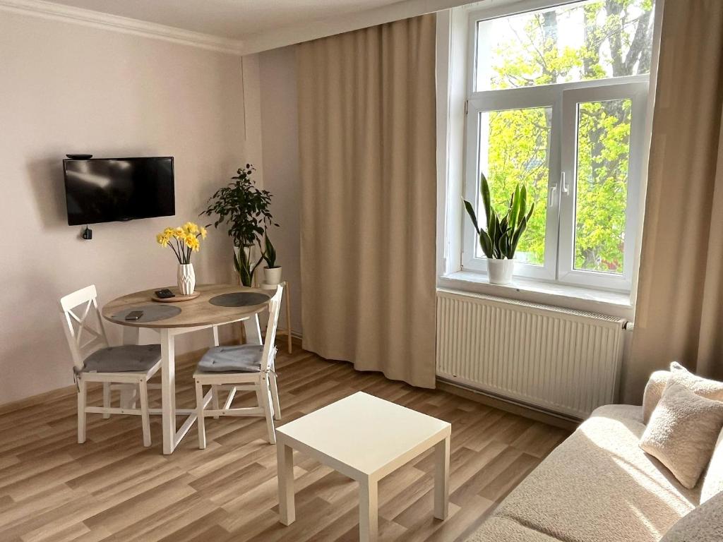 ein Wohnzimmer mit einem Tisch, Stühlen und einem Fenster in der Unterkunft Noclegi Pod Klonem in Sandomierz