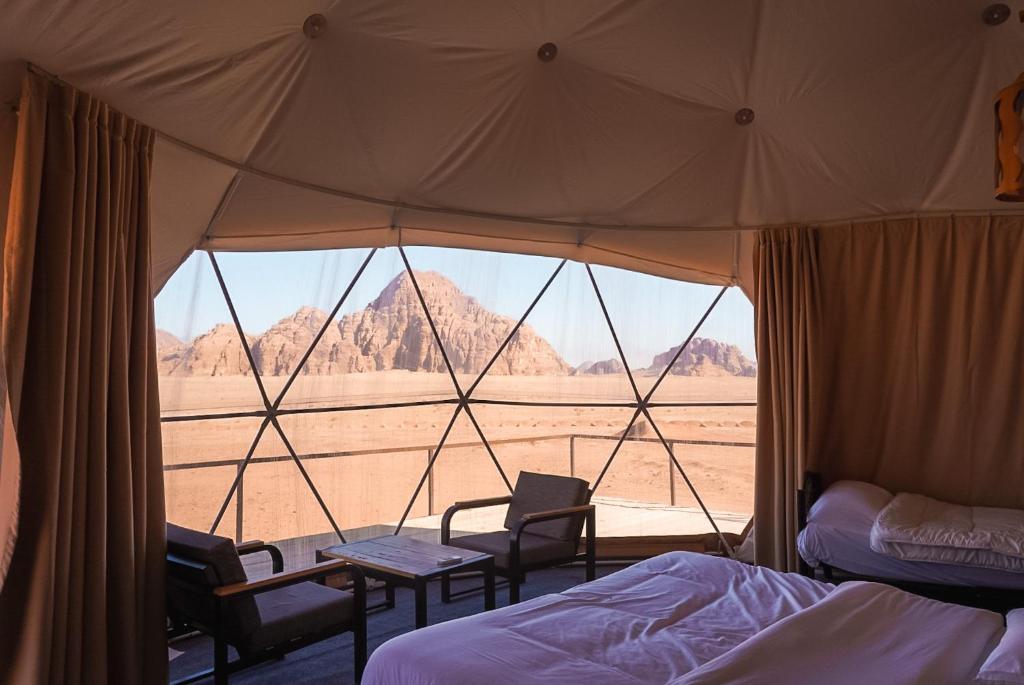 a tent with two beds and a view of the desert at Mirage Camp Wadi Rum in Wadi Rum