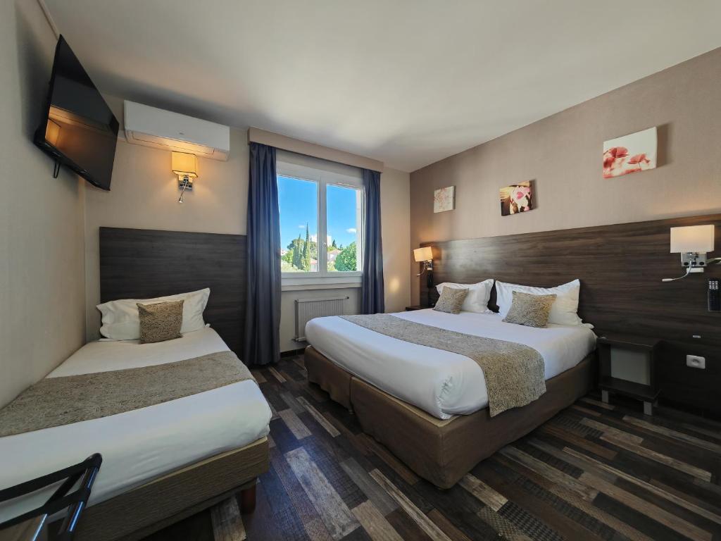 ラ・シオタにあるオテル ラ ロトンドのベッド2台と窓が備わるホテルルームです。